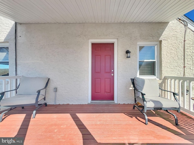 doorway to property featuring a porch and stucco siding