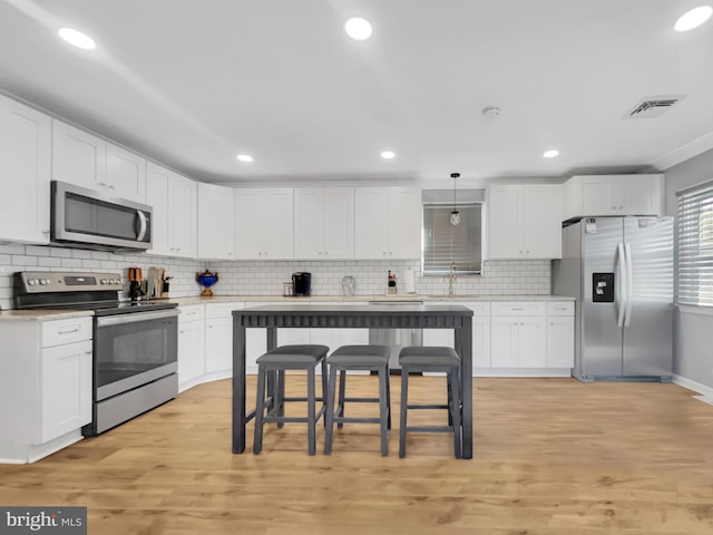 kitchen with visible vents, light countertops, light wood-style floors, white cabinets, and stainless steel appliances