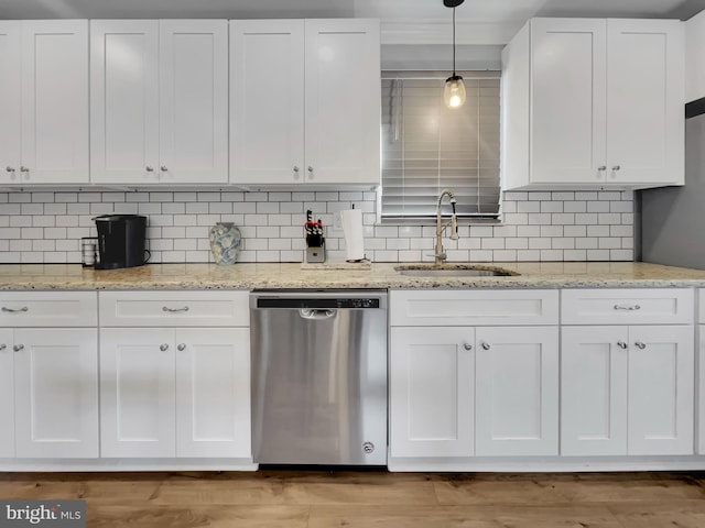 kitchen with pendant lighting, a sink, tasteful backsplash, stainless steel dishwasher, and white cabinets