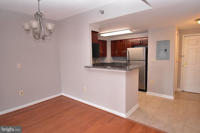 kitchen featuring electric panel, baseboards, freestanding refrigerator, and a sink