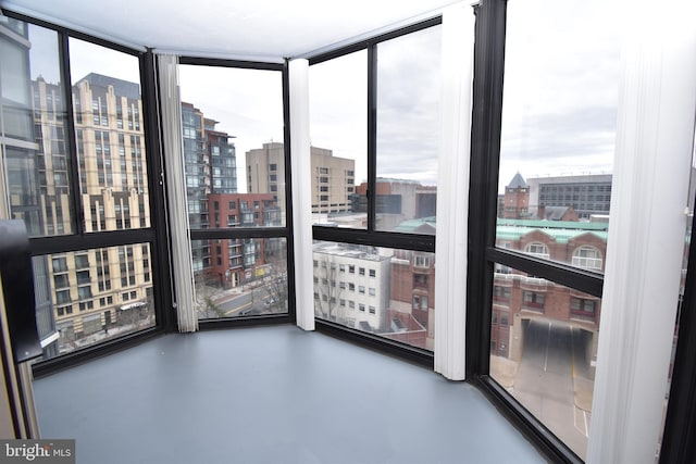 interior space featuring a view of city, a wall of windows, and finished concrete flooring