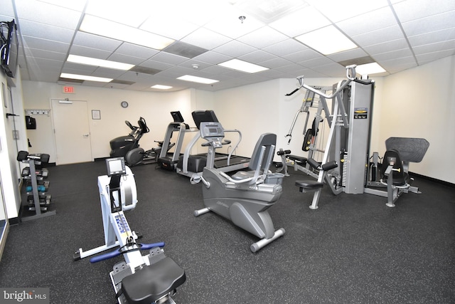 exercise room with a paneled ceiling and baseboards