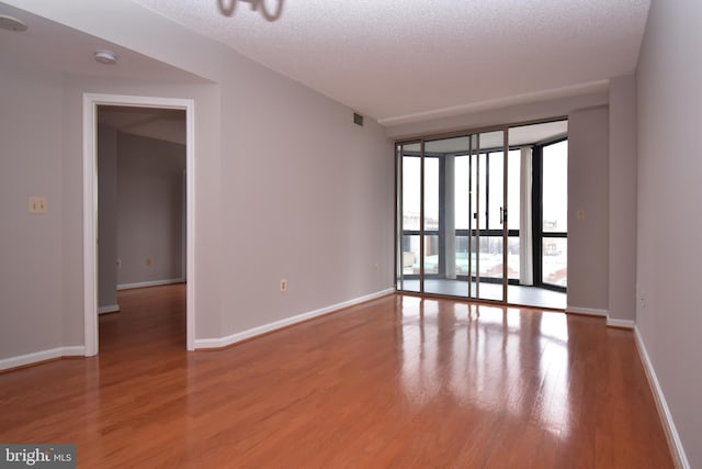 empty room featuring visible vents, light wood-style floors, baseboards, and a textured ceiling