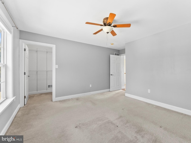 unfurnished bedroom with a spacious closet, visible vents, baseboards, carpet flooring, and a closet