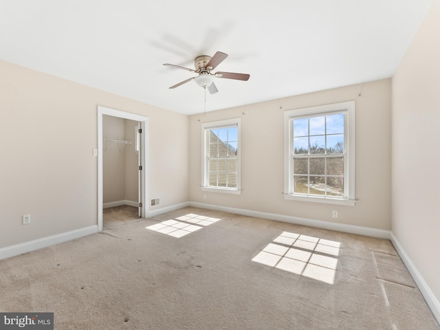 unfurnished bedroom featuring visible vents, baseboards, a closet, a walk in closet, and carpet flooring