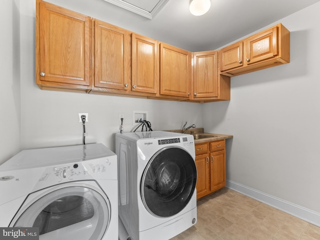 clothes washing area featuring a sink, cabinet space, baseboards, and washer and clothes dryer