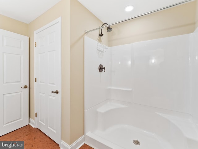 bathroom featuring a shower and baseboards