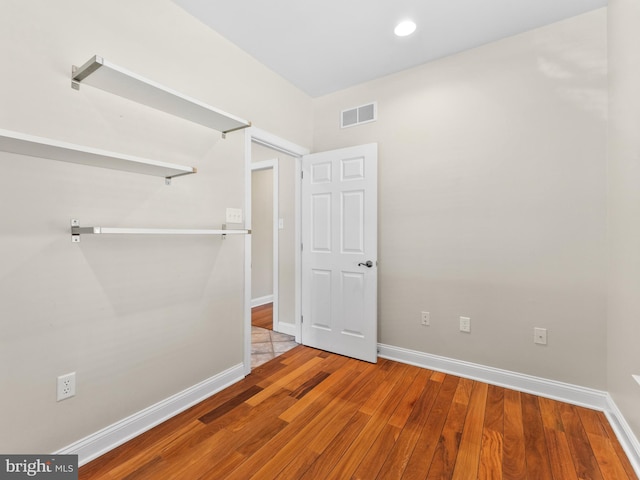 unfurnished bedroom featuring visible vents, baseboards, and wood finished floors