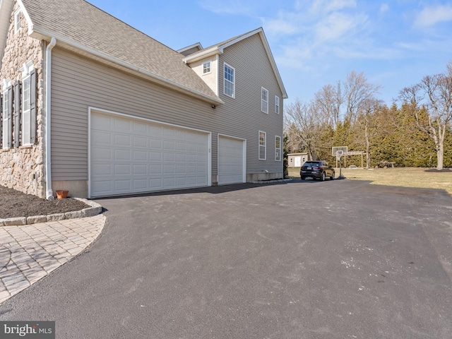 view of property exterior featuring aphalt driveway and roof with shingles