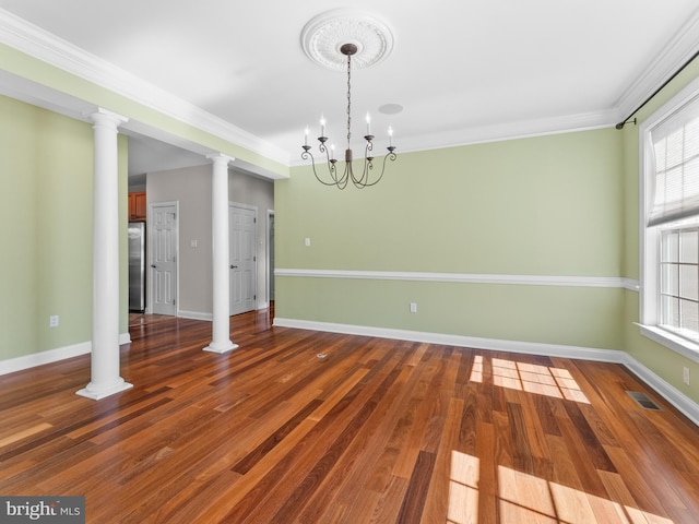 unfurnished dining area featuring wood finished floors, visible vents, baseboards, ornamental molding, and a chandelier