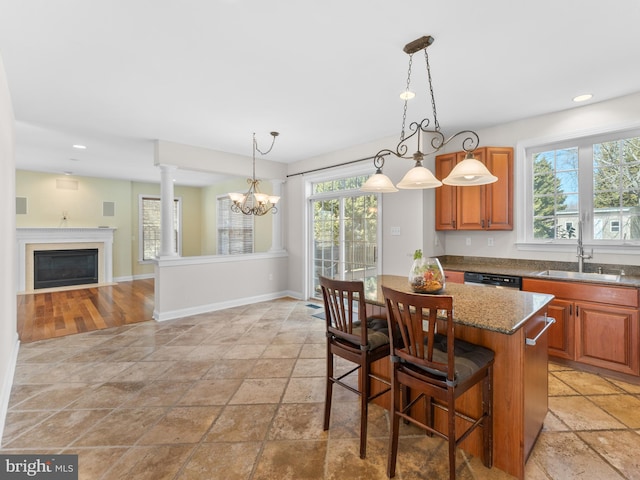 kitchen featuring a center island, dishwashing machine, a notable chandelier, stone countertops, and a sink