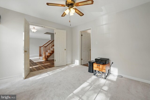 carpeted spare room with ceiling fan, baseboards, and stairway