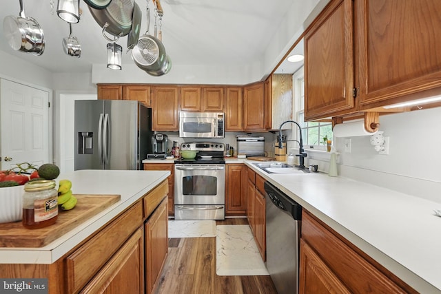 kitchen featuring a sink, light countertops, brown cabinetry, and stainless steel appliances