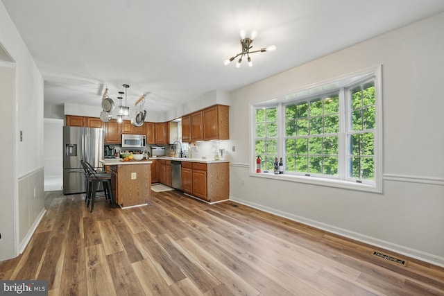 kitchen featuring appliances with stainless steel finishes, wood finished floors, and a notable chandelier
