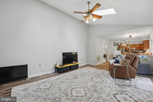living room featuring ceiling fan, visible vents, a skylight, and wood finished floors