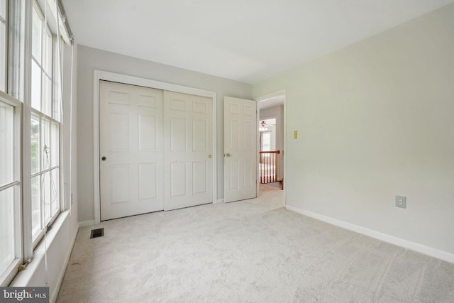 unfurnished bedroom featuring baseboards, carpet, a closet, and visible vents