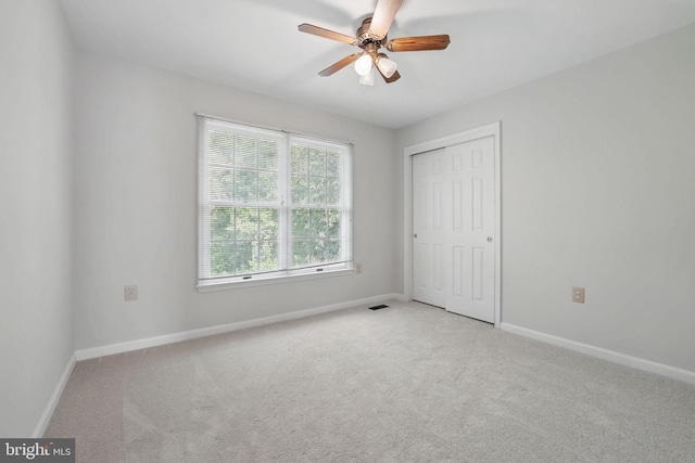 unfurnished bedroom featuring baseboards, light carpet, and a closet