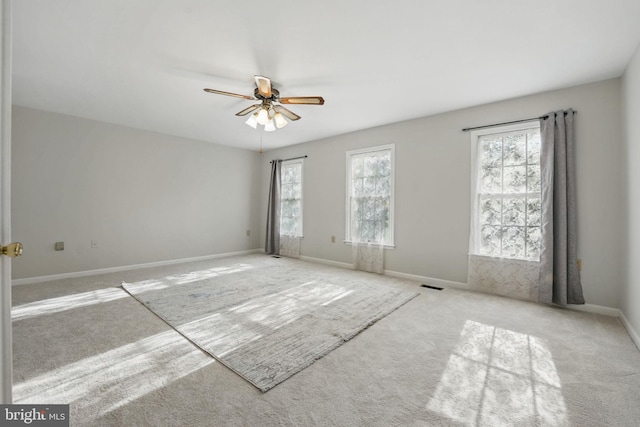 carpeted empty room with visible vents, baseboards, and ceiling fan