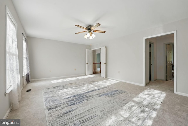 unfurnished room with visible vents, a ceiling fan, baseboards, and light carpet
