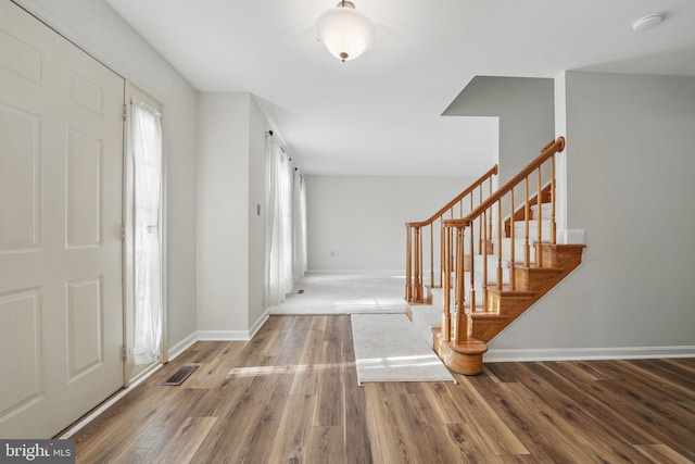 entryway with visible vents, baseboards, wood finished floors, and stairway