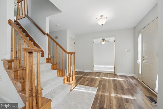 entrance foyer featuring visible vents, a ceiling fan, wood finished floors, and stairway