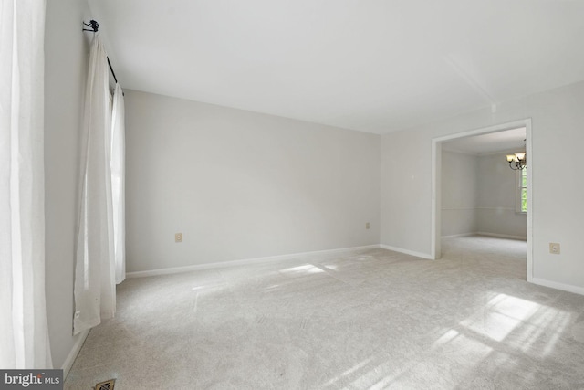 unfurnished bedroom featuring baseboards, light carpet, and a notable chandelier