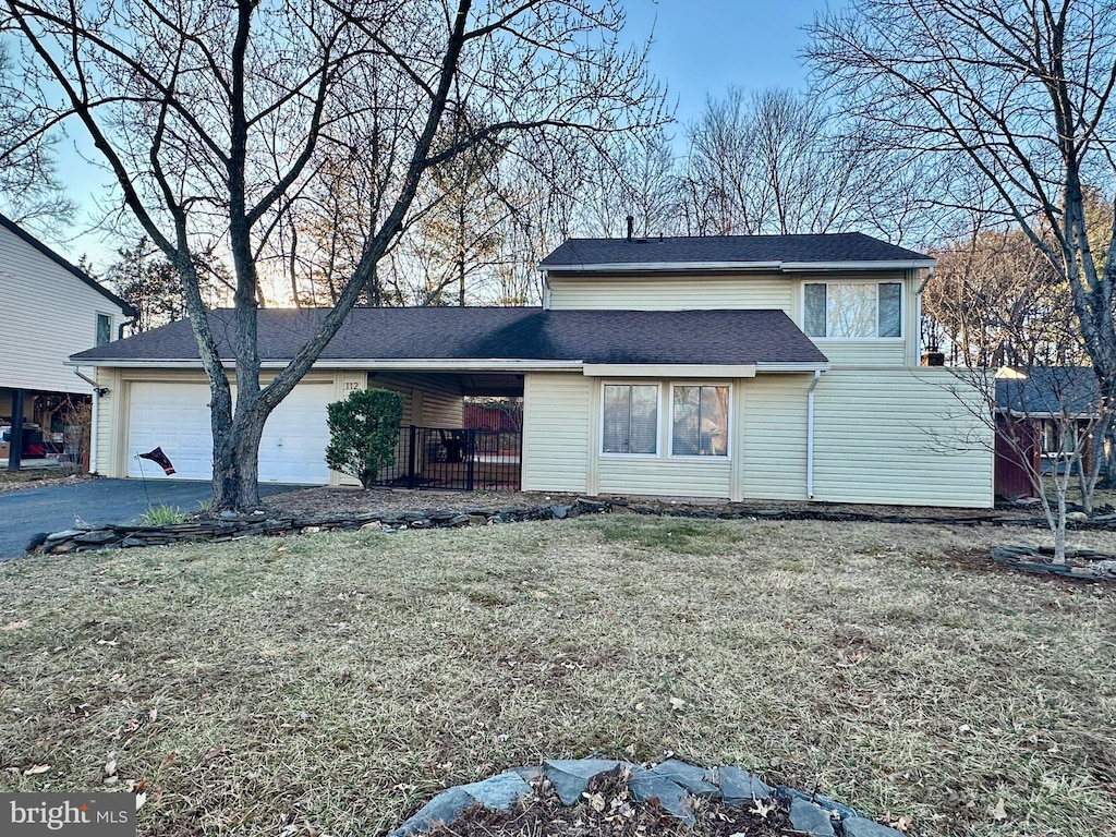 traditional-style house featuring a front yard, an attached garage, and driveway