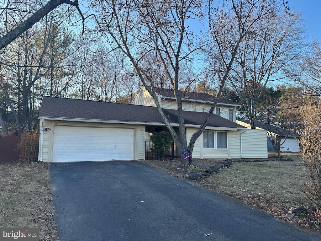 traditional-style home featuring an attached garage, driveway, and roof with shingles