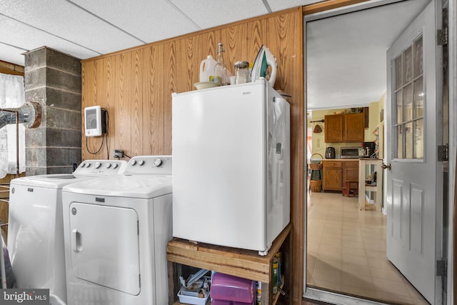 clothes washing area featuring washer and dryer, laundry area, wooden walls, and a toaster