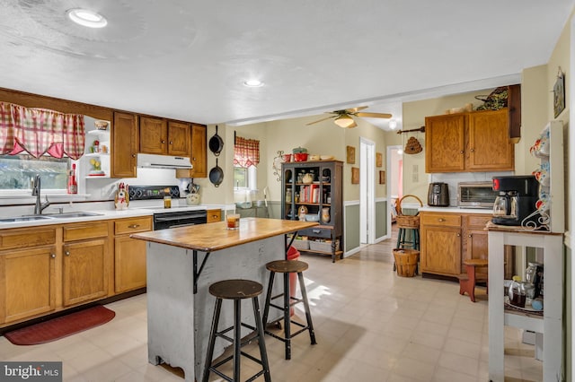 kitchen with light floors, light countertops, electric range oven, and a sink