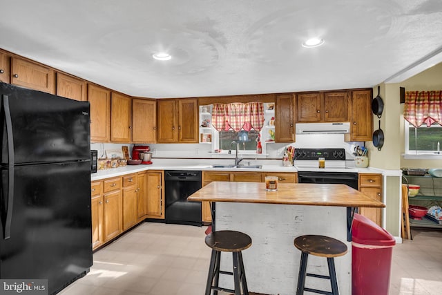 kitchen with black appliances, a sink, a kitchen breakfast bar, light countertops, and extractor fan