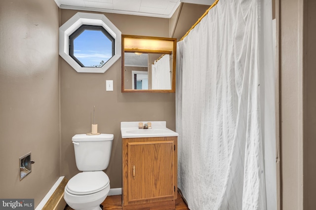 bathroom with toilet, vanity, and wood finished floors