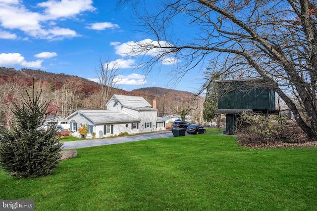 view of yard with aphalt driveway and a mountain view