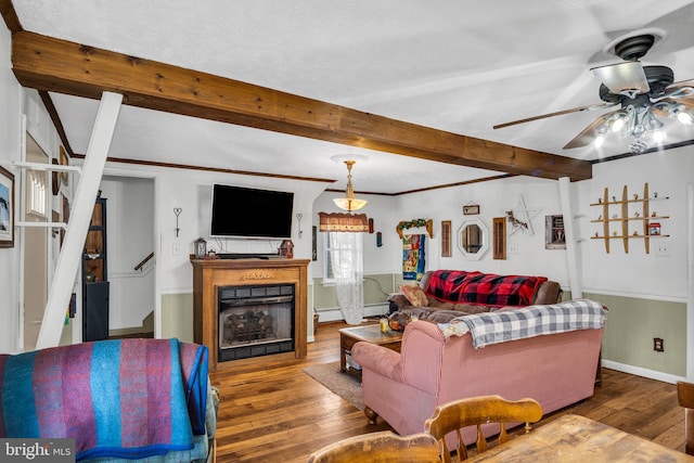 living room featuring hardwood / wood-style floors, a ceiling fan, a fireplace, beamed ceiling, and baseboard heating