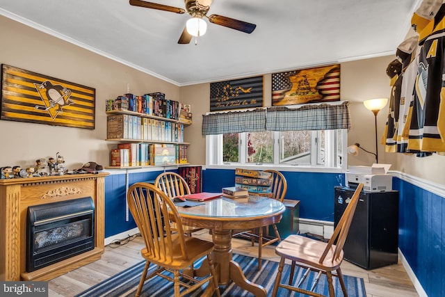 dining area featuring a fireplace, wood finished floors, ceiling fan, and ornamental molding