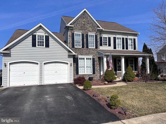 view of front of property featuring a front yard, roof with shingles, a garage, stone siding, and aphalt driveway