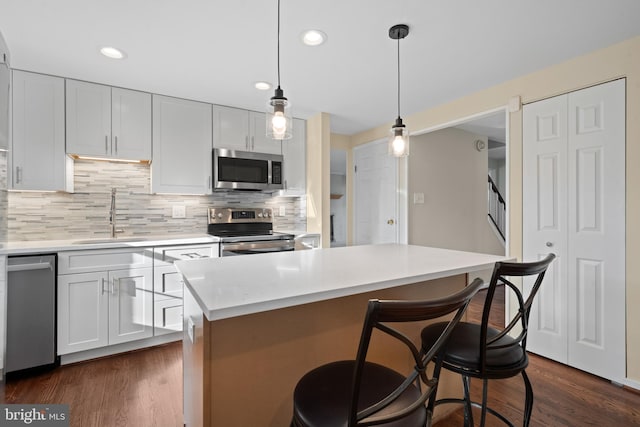 kitchen featuring stainless steel appliances, light countertops, dark wood-type flooring, and a sink