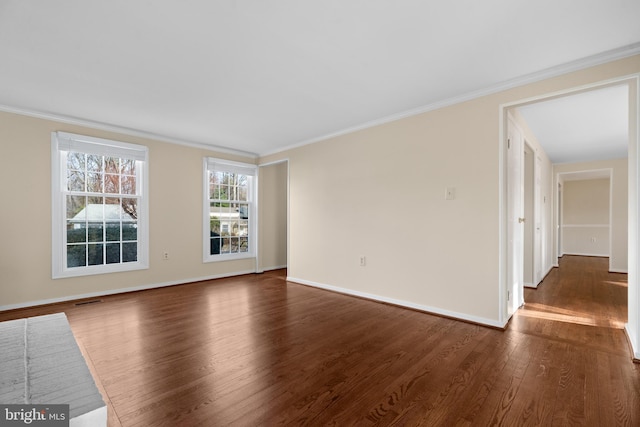 empty room with visible vents, baseboards, dark wood-style floors, and crown molding