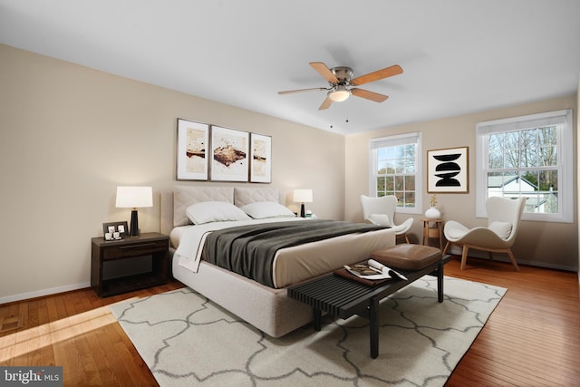 bedroom featuring baseboards, hardwood / wood-style floors, and a ceiling fan