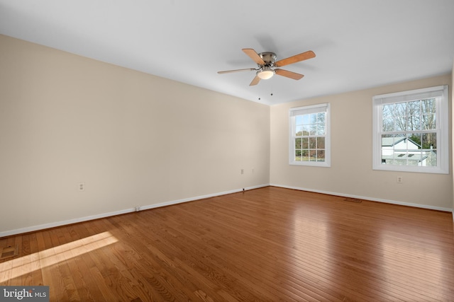 unfurnished room featuring baseboards, wood-type flooring, visible vents, and a ceiling fan