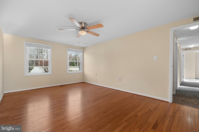 unfurnished room with hardwood / wood-style floors, visible vents, a ceiling fan, and baseboards