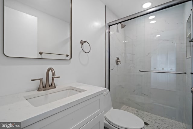 full bath with a marble finish shower, toilet, and vanity