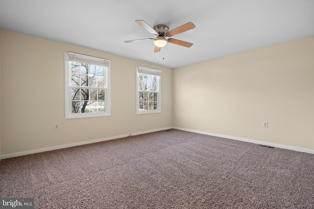 carpeted spare room with visible vents, a ceiling fan, and baseboards