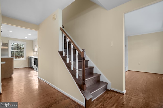 stairs featuring a stone fireplace, recessed lighting, wood finished floors, and baseboards