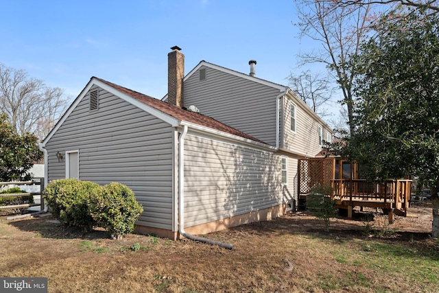 view of side of property with a chimney and a wooden deck