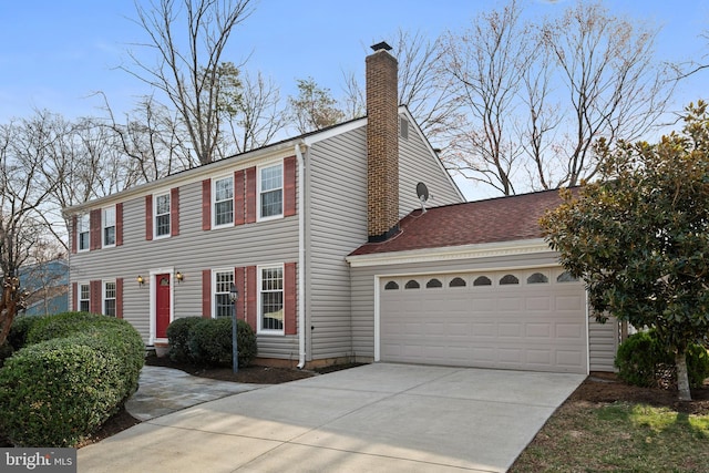 colonial inspired home with driveway, an attached garage, and a chimney