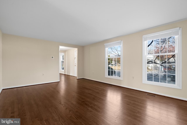 unfurnished living room with visible vents, baseboards, and dark wood-style flooring