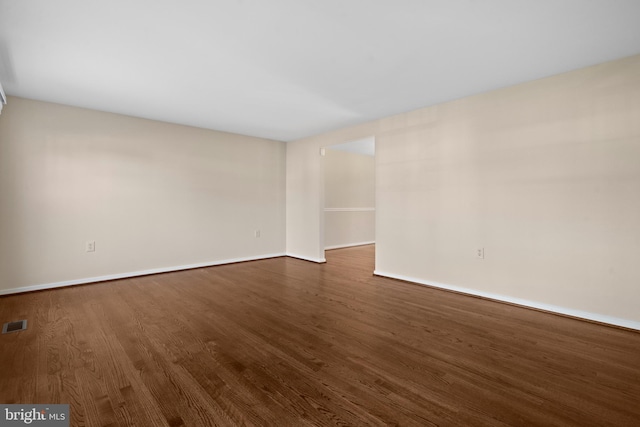 spare room with visible vents, dark wood-type flooring, and baseboards