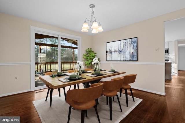 dining area with a notable chandelier, wood finished floors, visible vents, and baseboards