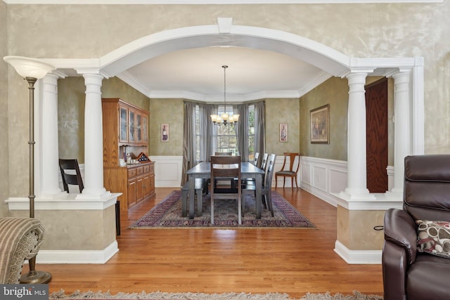 dining area with light wood-style floors, arched walkways, and ornate columns